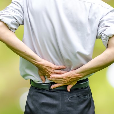 close up of a man holding his back in pain.
