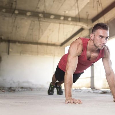 Muscular, athletic built, young man doing pushups in an abandoned ruin building