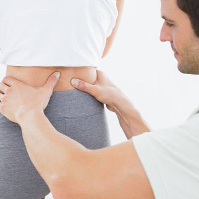Mid section of a physiotherapist examining woman's back
