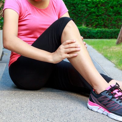 Asian sporty woman leg pain or calf muscle while jogging