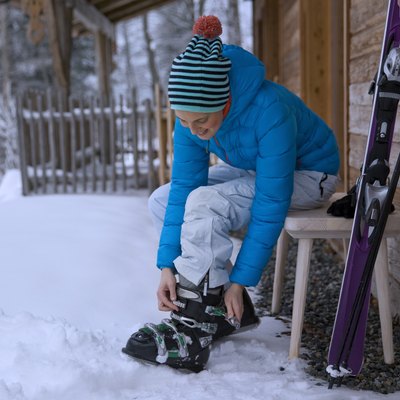 Woman adjusting ski boots in snow