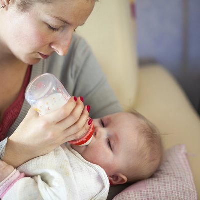 Mother feeding infant girl with a milk bottle