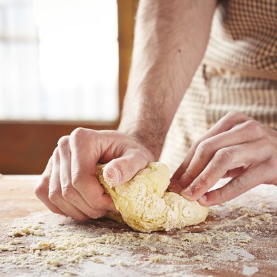 Hands baking dough on wooden table