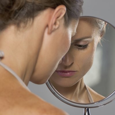 stressed young woman looking in mirror