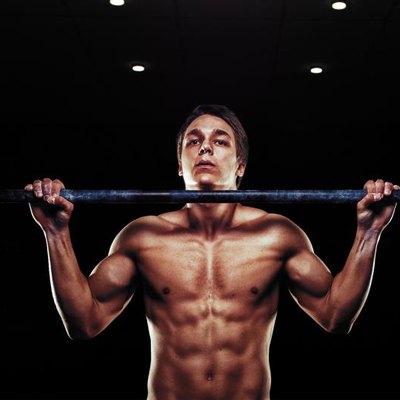Young muscular man doing pull ups exercise on horizontal bar. Sports, fitness concept.