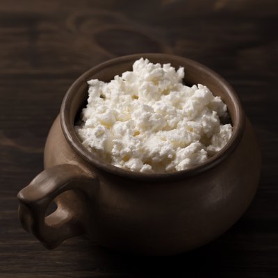 fresh tasty curd in pot on wooden background.