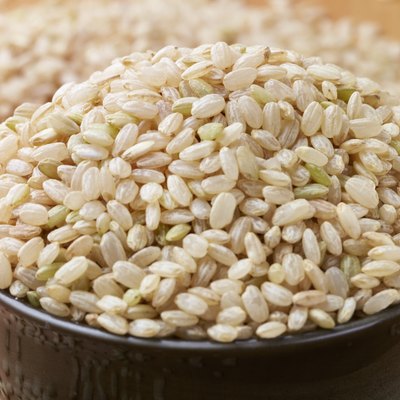 uncooked brown rice in a bowel with woody background