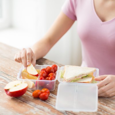 close up of woman with food in plastic container