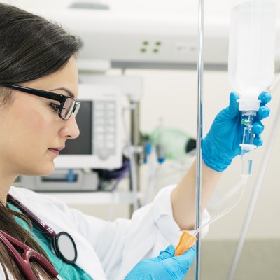 Young woman doctor anesthesiologist dressed in green gown, puts