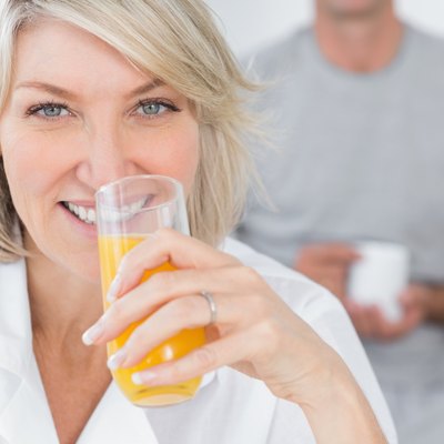 Happy woman drinking orange juice in kitchen