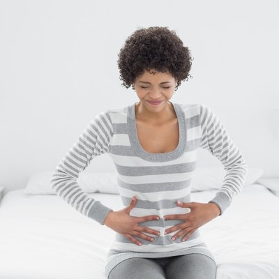 Casual woman with stomach pain sitting in bed