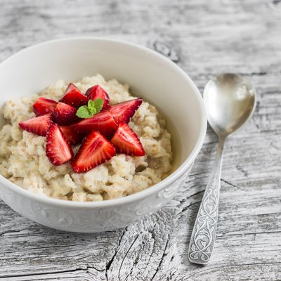 oatmeal with honey and strawberries in a white bowl