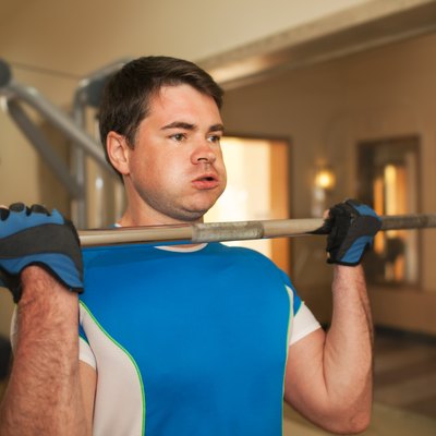 Strong young man exercising with barbell