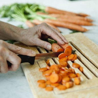 Germany, Berlin, Senior man cutting carrots