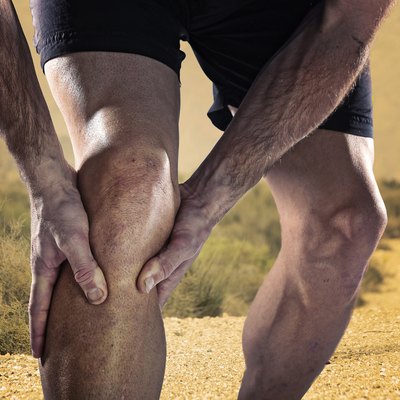 sportsman athletic legs holding knee in pain suffering muscle injury
