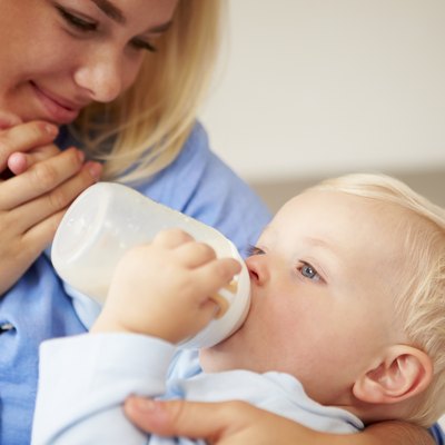 Mother Giving Baby Son Bottle Of Milk
