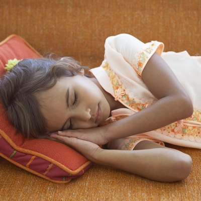 Girl (7-9) sleeping on sofa, resting head on cushion, close-up