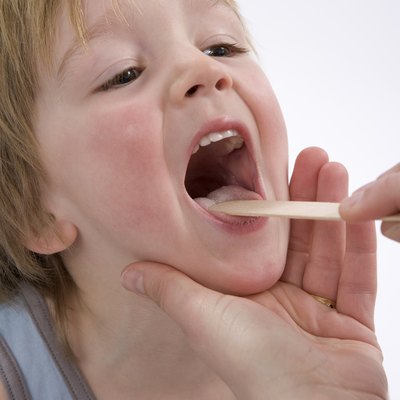 Doctor is looking into the mouth of a little boy