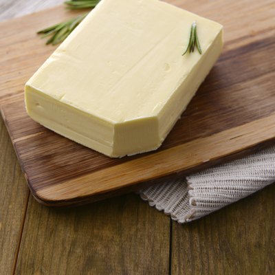 Tasty butter on wooden cutting board