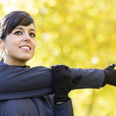 Beautiful sportswoman stretching shoulder and arm outdoors