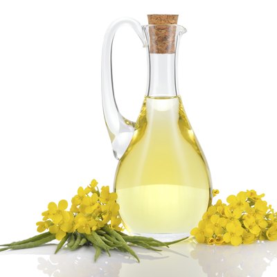 Rapeseed oil and flowers isolated over white.