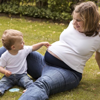 Young pregnant woman and little son in autumn garden