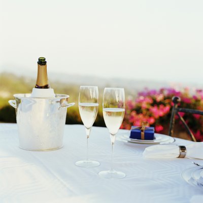 Two glasses of champagne on table, bottle in ice bucket in background