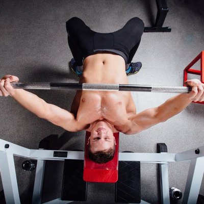 young bodybuilder training in the gym: chest - barbell incline bench press - wide grip, top view