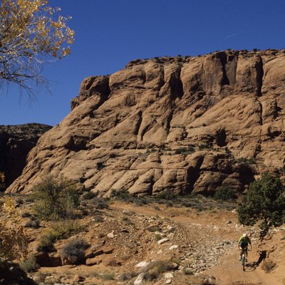 Mountain biker on trail in front of cliff, elevated view