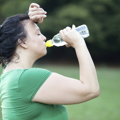 Sweaty overweight woman drinking water after a long run