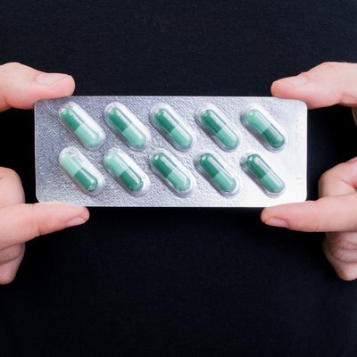 Hands holding blister with green pills