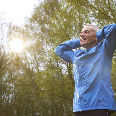 Mature Male Runner Stretching Arms In Park