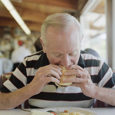 A senior man eating a hamburger