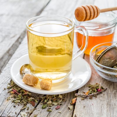 Herbsl tea in glass cup, honey, rustic wood background