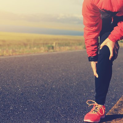 woman runner hold her injured leg on road
