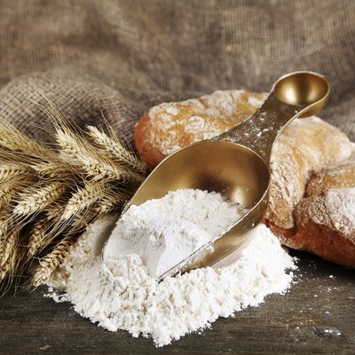 The wholemeal flour in scoop on wooden table