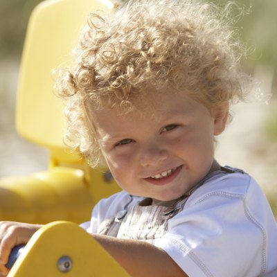 Toddler boy (2-4) sitting in playground ride, smiling, portrait