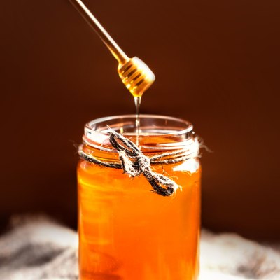 Fresh Honey in jar with dipper on vintage wooden