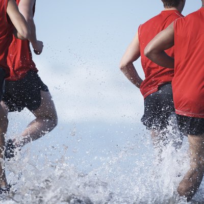 Men running in ocean, low section