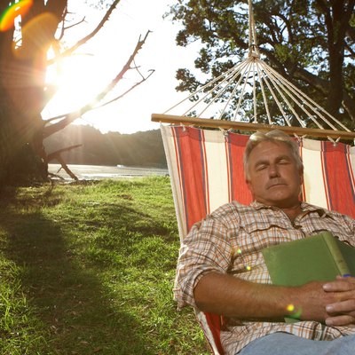 Mature man sleeping in hammock (lens flare)