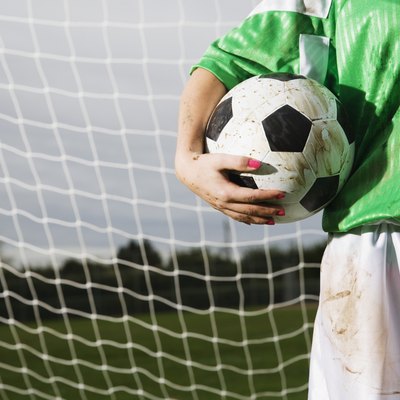 Lower section of girl holding soccer ball