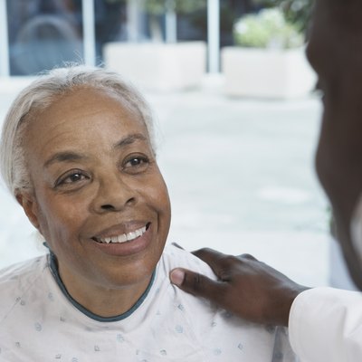 Senior African woman smiling at African doctor in hospital
