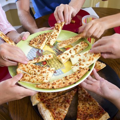 Hands taking slices of pizza