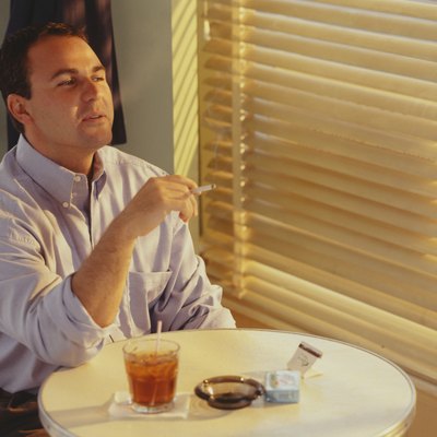 Man smoking, drinking in bar at table