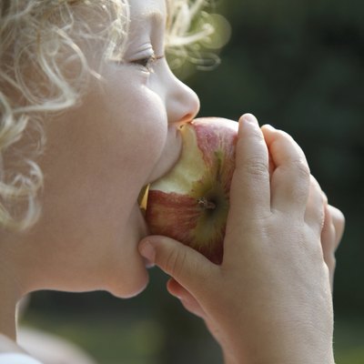 "Girl (3-5) biting into apple, profile, close-up"