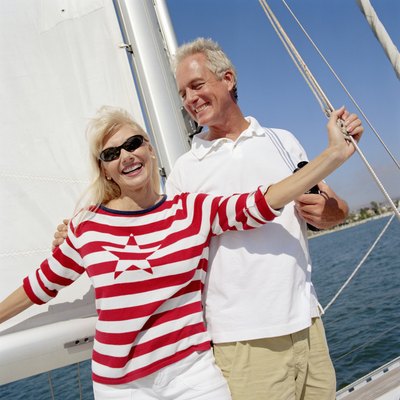 Mature couple standing on yacht, smiling
