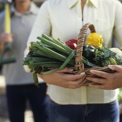 Woman holding basket of vegetables, close up, mid section