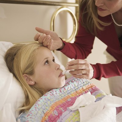Girl with fever lying down in bed indoors