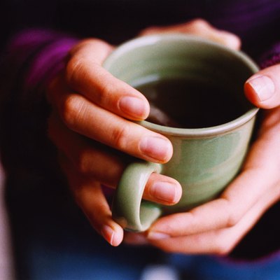 high angle view of hands holding a cup of coffee
