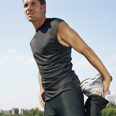 Male runner stretching leg in park, low angle view